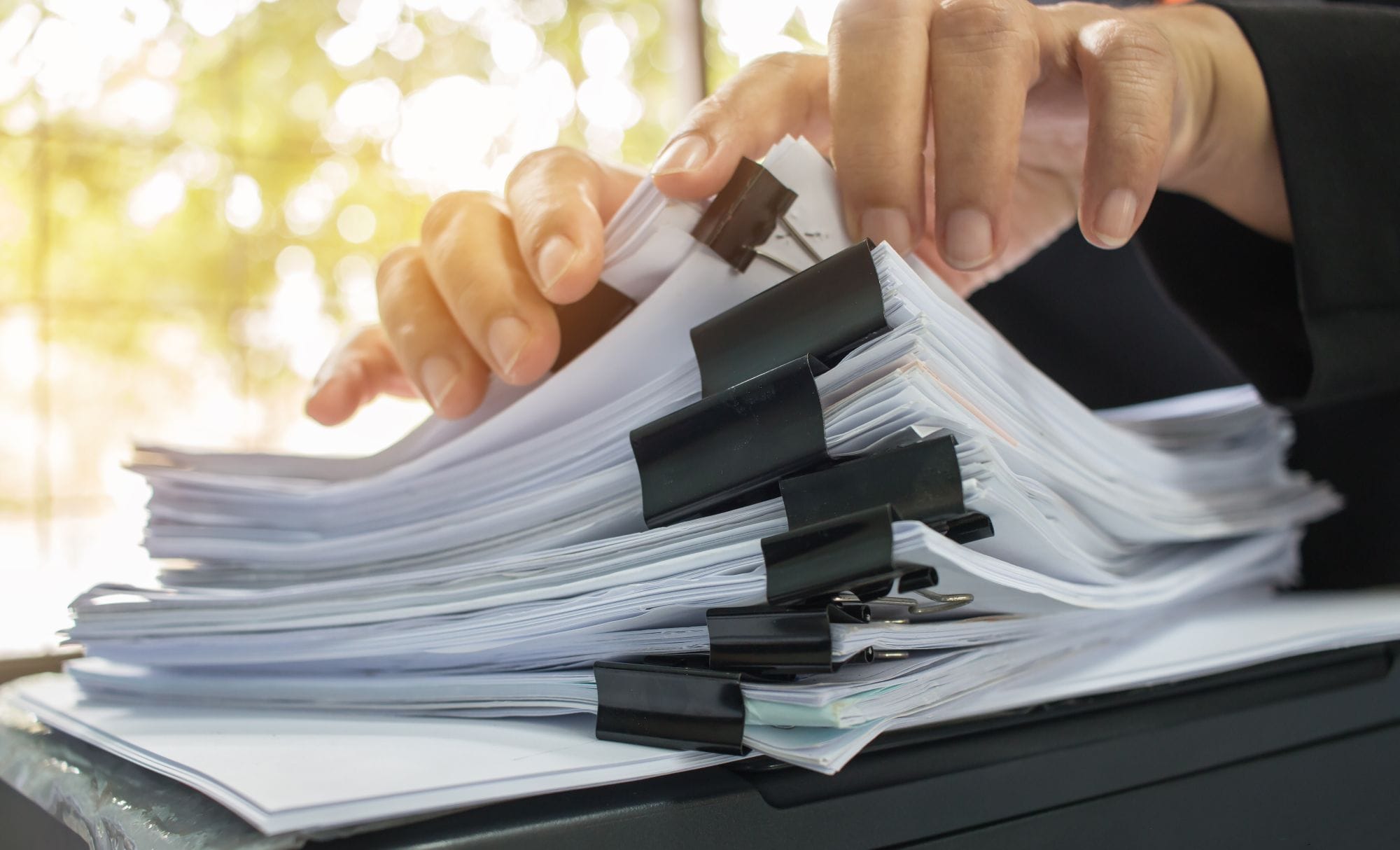businessman hands working in stacks of paper files for searching